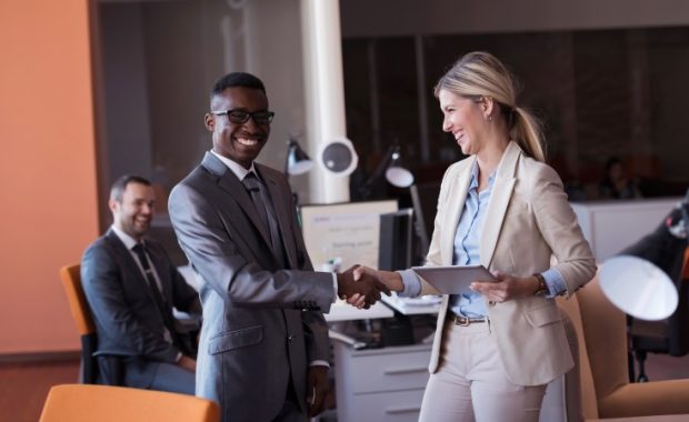 A female supervisor shaking the hand of a male coworker.