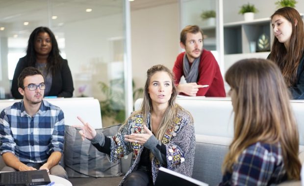 Employees sitting on couches drinking coffee and talking about business.