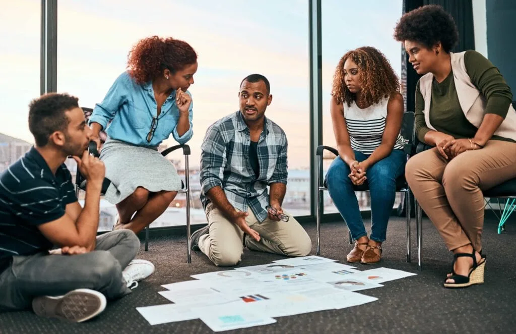 A diverse professional team brainstorming and reviewing strategy documents during a collaborative meeting in a bright office in Charlotte, NC.