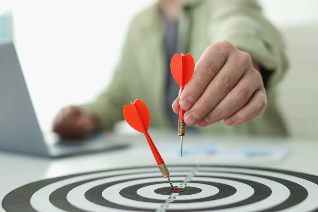 A close-up shot of a red and white dartboard with a targeted retention strategies with single silver dart hitting a perfect bullseye in the center, symbolizing successful corporate sales training in New York, NY.