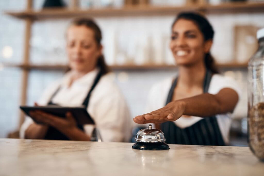 A young woman looking stressed while talking on a phone at a hotel front desk, illustrating hospitality burnout burnout in the hospitality industry in Miami, FL.