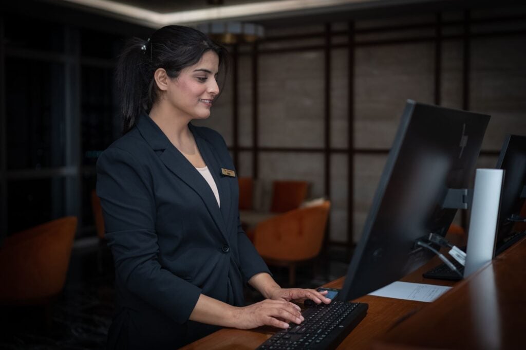 frontline employees at a hotel front desk smiling with a manager, illustrating retention of frontline employees.